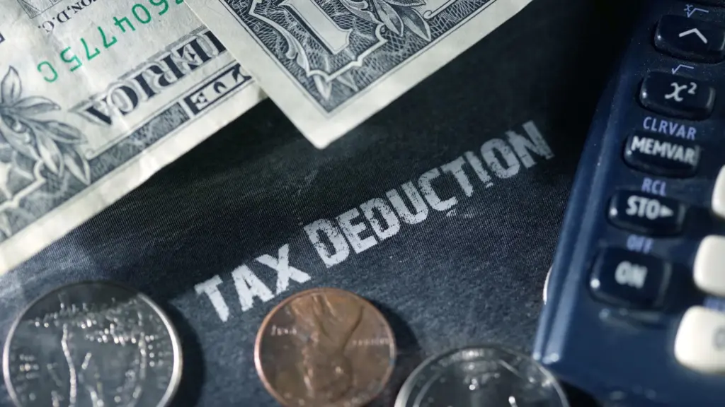 A Tax Deduction folder with money and a calculator on top. 