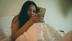 A woman looking through her phone while in bed. 