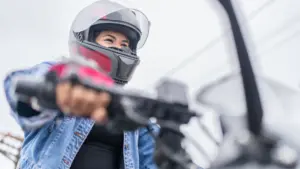 A person riding a moped while wearing a helmet. 