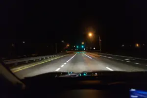 A car driving with its high beams on, brightening up the road. 