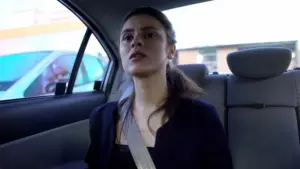 A concerned woman in the back seat of a car.