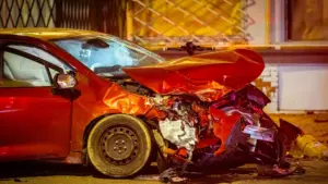 A red car in a severe car accident at night. 