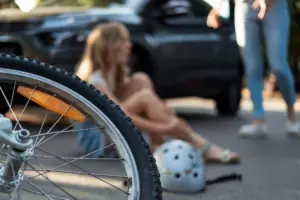 A woman on the ground in pain and another person coming to help. 