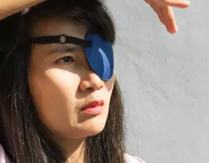 A woman with an eye patch staring outward. 