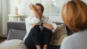 A crying woman talking to someone on the couch. 
